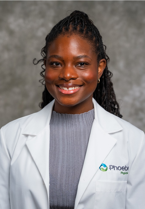 Dr. Kikelomo Olaosebikan, wearing a white medical coat over a gray top, posed before a mottled gray background. Dr. Kikelomo Olaosebikan, wearing a white medical coat over a gray top, posed before a mottled gray background.