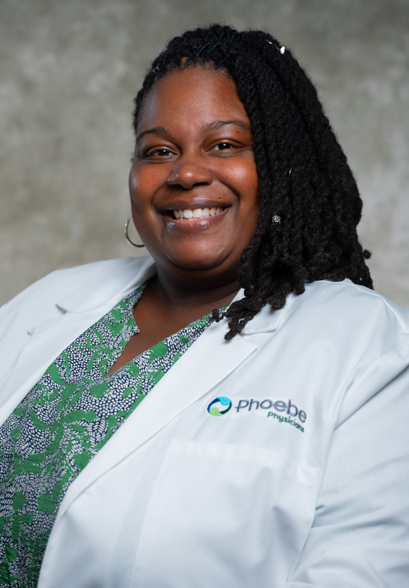 Bratisha Bradley, a healthcare professional, smiles while wearing a white coat with the Phoebe Physicians logo. Bratisha Bradley, a healthcare professional, smiles while wearing a white coat with the Phoebe Physicians logo.
