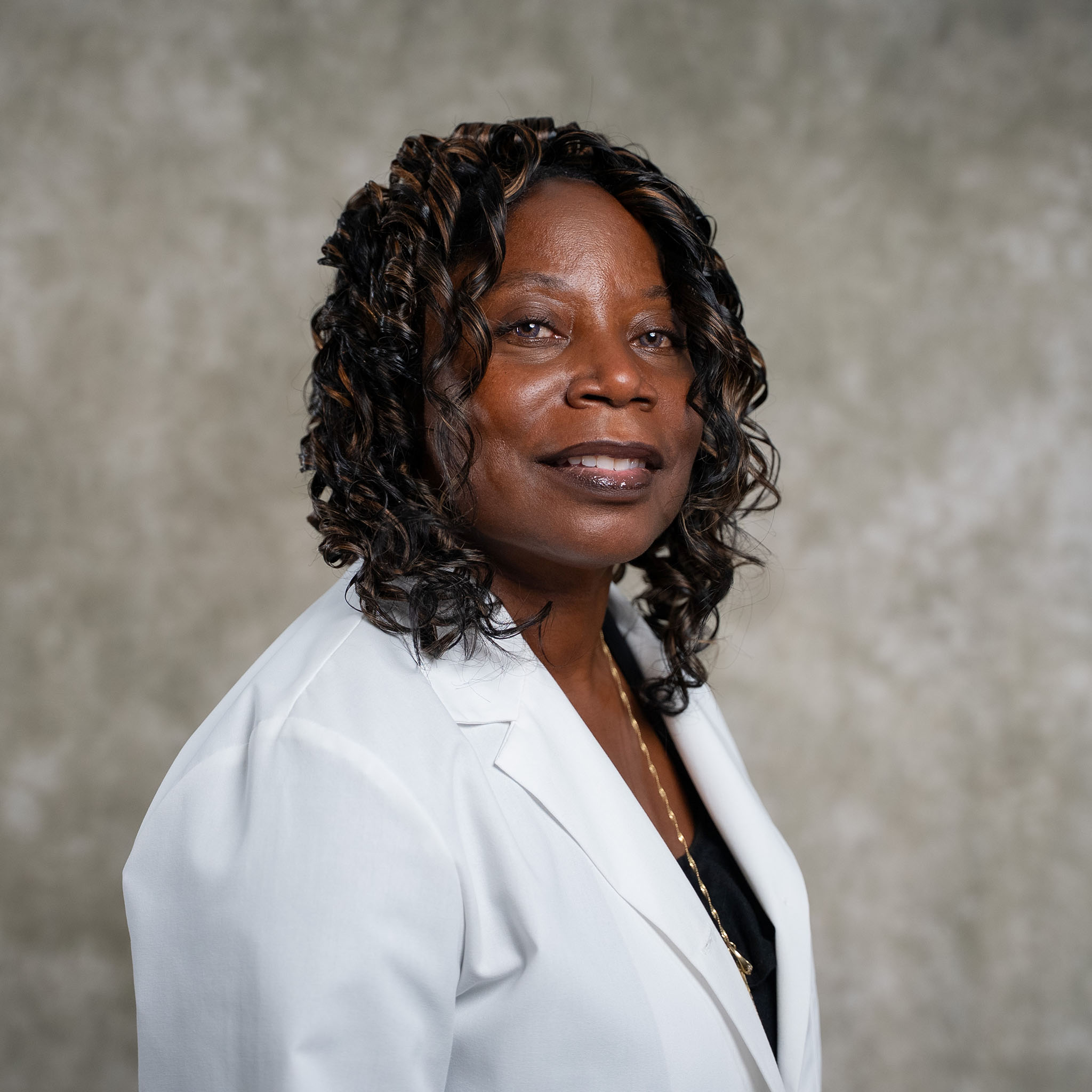 Lorena Doctor, a woman in a white blazer, smiles at the camera. Lorena Doctor, a woman in a white blazer, smiles at the camera.