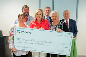 Six people smile and hold a $10,000 ceremonial check from Phoebe Honors for Horizons Community Solutions, dated July 17, 2023.