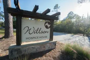 A wooden sign with stone base reads Willson Hospice House beside a road, marking the nationally recognized Phoebe Hospice site.