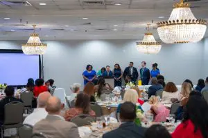 A group stands at a podium in a banquet hall with chandeliers, celebrating faculty and the Family Medicine Residency Class of 2025.