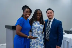 Three people pose and smile indoors, dressed formally, celebrating their Family Medicine Residency with Outstanding Faculty.