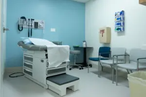 A clean exam room at Phoebe Clinic with an exam table, chairs, and medical supplies on the walls.