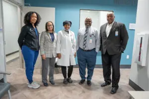 Five professionals, including a doctor in a lab coat, smile together in the hallway of Laurel Place’s primary care office.