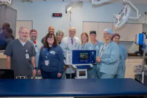 Smiling medical staff pose in a hospital operating room, surrounded by advanced technology and medical equipment.