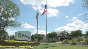 Sign for Phoebe Worth with building, flowers, two flags, and blue sky—part of the Phoebe Hospitals system in Southwest Georgia.