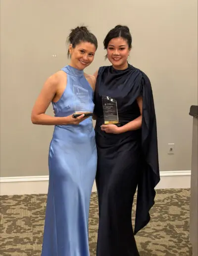 Two women in elegant dresses, smiling and holding awards—proud graduates of the Family Medicine Residency Class of 2026 at Phoebe.
