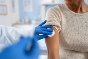 Despite Confusion over Vaccine Guidance Phoebe Says the Medical Recommendation Hasn’t Changed 2 A healthcare worker cleans a woman’s upper arm with a cotton pad before administering a vaccine injection.