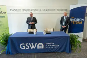 Two men stand at a GSW logo table inside the Phoebe Simulation & Learning Center, highlighting a Southwest Georgia partnership.