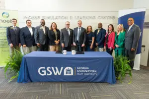Eleven people stand and smile behind a table highlighting a Georgia Southwestern State University healthcare partnership.