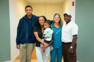 Five people, including a nurse, smile in a hallway at the Sumter Pink Walk for cancer; a woman holds a toddler.