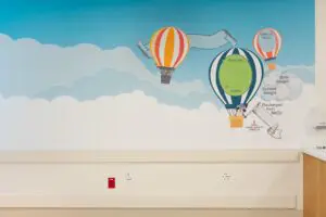 A NICU mural with colorful balloons and milestone details on dreamy clouds celebrates families and babies’ journeys.