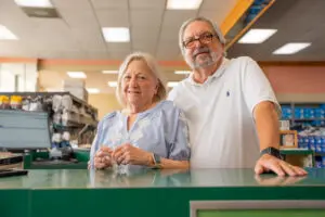Bob Mulford and Debbie Mulford stand together behind a green counter, reflecting “Together Through Every Step.”