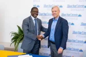 Two men shaking hands in front of an Albany State University backdrop during a partnership event with the Phoebe organization.