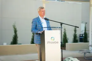 A man in a blue plaid blazer speaks at a podium branded for Phoebe Emergency at the Level II Trauma Center.