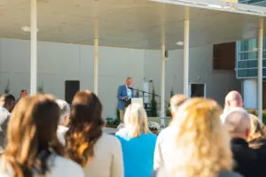 A man in a blue blazer speaks at a podium to an outdoor audience at the Phoebe Emergency Level II Trauma Center.