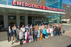 A large group of healthcare professionals standing in front of the Emergency and Level II Trauma Center entrance.