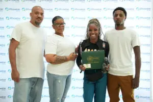 Four people stand before a Phoebe Sumter Medical Center backdrop, with one holding a DAISY Award certificate and statuette.