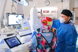 Two medical professionals in protective clothing collaborate in a hospital room, adjusting monitors during a Milestone Advanced Lung Procedure.