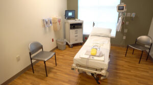 A hospital room with a bed, medical equipment, chairs, and supplies highlights efforts to promote colon cancer awareness.