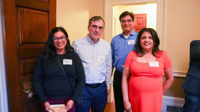 Four adults from the Phoebe Physicians Group stand indoors near a wooden door, smiling at the camera during the Annual Banquet. One woman holds a plate of food, and everyone is dressed in business casual attire.